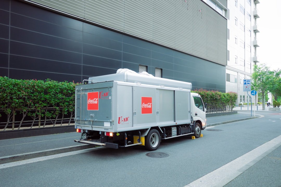 a-grey-coca-cola-delivery-truck-drives-on-a-city-street-d5dwueytdjq